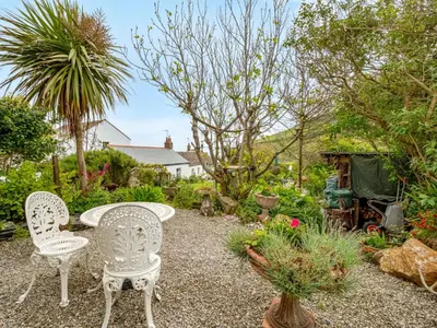 a patio with two chairs and a table in a garden at Holiday Home The Homestead by Interhome in Gorran Haven
