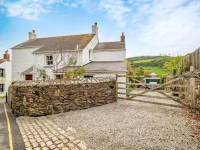 a stone wall in front of a white house at Holiday Home The Homestead by Interhome in Gorran Haven