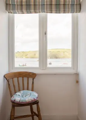 a wooden chair sitting in front of a window at Castle House - Penthouse in Polruan