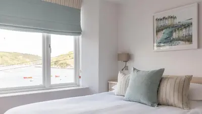 a bedroom with a bed and a large window at Castle House - Penthouse in Polruan