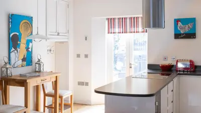 a kitchen with white cabinets and a counter top at Castle House - Penthouse in Polruan