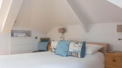 a bedroom with a white bed with blue pillows at Castle House - Penthouse in Polruan