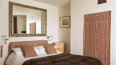 a bedroom with a bed with a mirror on the wall at Castle House - Polruan in Polruan