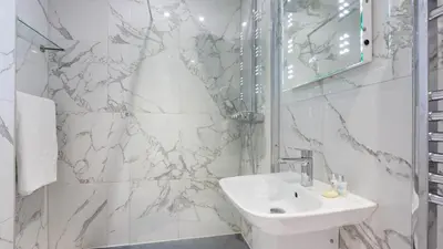 a white bathroom with a sink and a mirror at Castle House - Polruan in Polruan