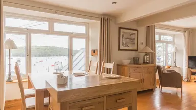 a dining room with a table and a view of the ocean at Castle House - Polruan in Polruan