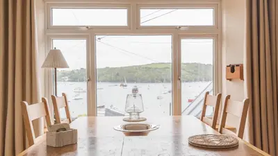 a dining room table with a view of the water at Castle House - Polruan in Polruan