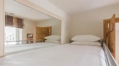 a white bedroom with two beds and a mirror at Castle House - Polruan in Polruan