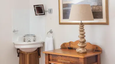 a bathroom with a sink and a lamp on a table at Castle House - Polruan in Polruan