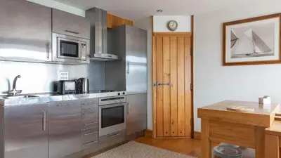 a kitchen with stainless steel appliances and a wooden table at Castle House - Polruan in Polruan