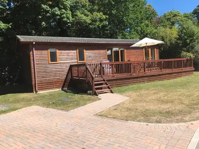 a log cabin with a deck and an umbrella at 10 Trehawks in Wadebridge