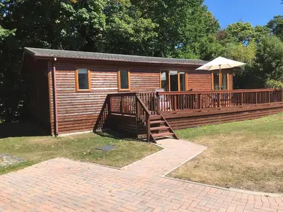 a log cabin with a deck and an umbrella at 10 Trehawks in Wadebridge
