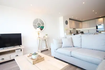 a living room with a white couch and a tv at Coastal apartment sea views in St Merryn