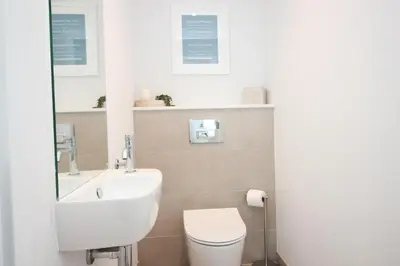 a bathroom with a white sink and a toilet at Coastal apartment sea views in St Merryn