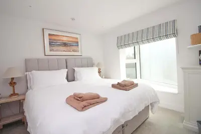 a bedroom with a white bed with towels on it at Coastal apartment sea views in St Merryn