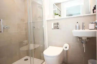 a bathroom with a shower and a toilet and a sink at Coastal apartment sea views in St Merryn