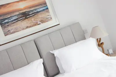 a bed with white pillows and a picture on the wall at Coastal apartment sea views in St Merryn
