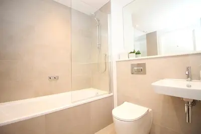 a bathroom with a toilet and a shower and a sink at Coastal apartment sea views in St Merryn