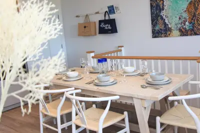 a dining room table with chairs and a wooden table at Coastal apartment sea views in St Merryn