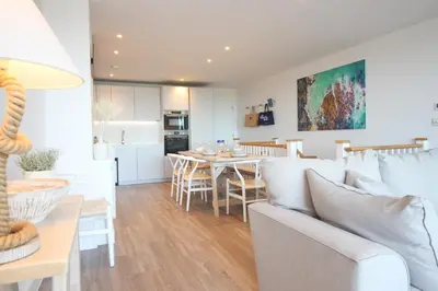 a living room and dining room with a couch and a table at Coastal apartment sea views in St Merryn
