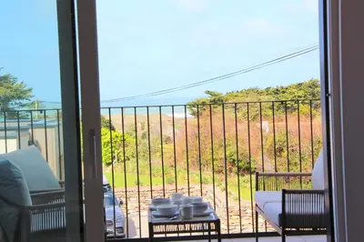 a room with a balcony with a view of the ocean at Coastal apartment sea views in St Merryn
