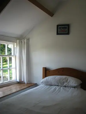 a bedroom with a bed and a window at The Old Farmhouse in Crackington Haven
