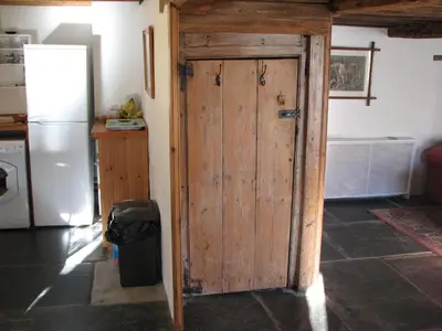 an open wooden door in a kitchen with a refrigerator at The Old Farmhouse in Crackington Haven