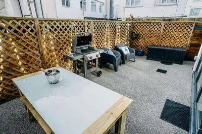 a patio with a white table and a grill at 3 Bedroom Holiday Home by beach in Newquay in Newquay