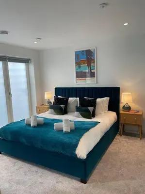 a bedroom with a large blue bed with pillows at 3 Bedroom Holiday Home by beach in Newquay in Newquay