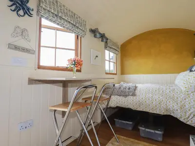 a bedroom with a bed and a desk and two stools at Dot May in Wadebridge