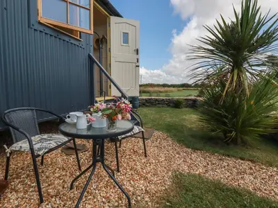 a patio with a table and chairs and a house at Dot May in Wadebridge