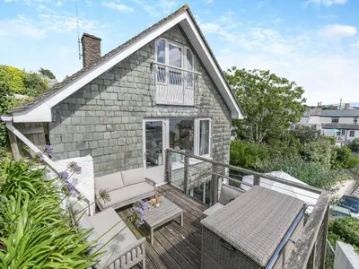 a house with a balcony with a table and chairs at Dolphins Reach in Saint Mawes
