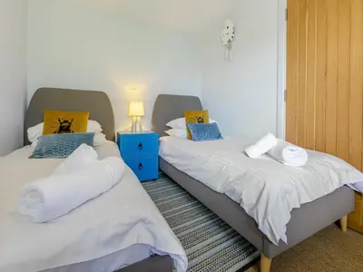 two twin beds in a room with a blue night stand at Dolphins Reach in Saint Mawes