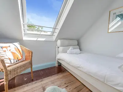 a room with a bed and a chair and a window at Dolphins Reach in Saint Mawes