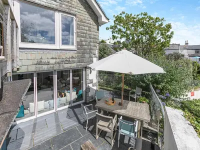 a patio with a table and an umbrella at Dolphins Reach in Saint Mawes