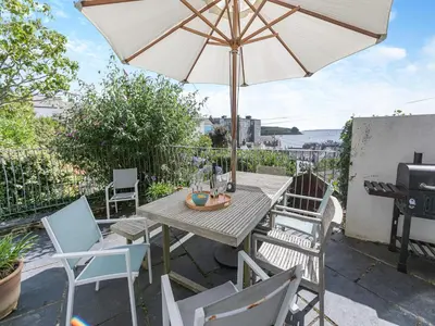a table and chairs with an umbrella on a patio at Dolphins Reach in Saint Mawes
