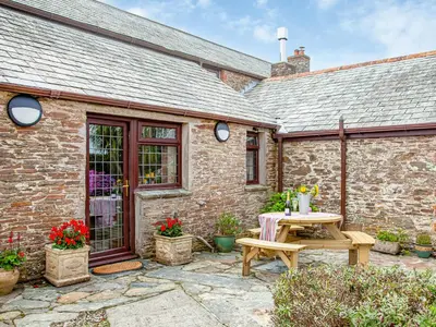 a stone house with a table and a bench at The Nook in Saint Ewe