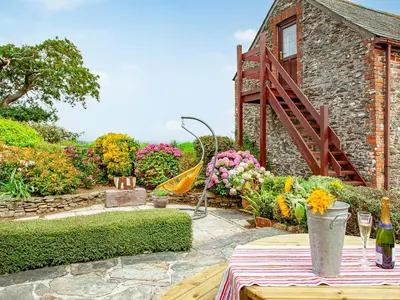a garden with a table and flowers and a building at The Nook in Saint Ewe