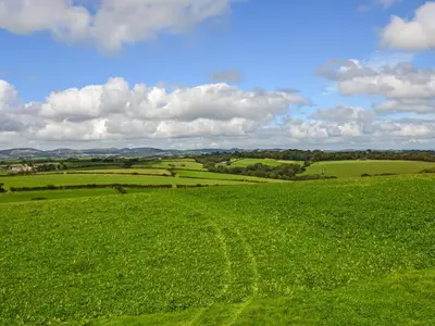a field of green grass with a blue sky and clouds at The Nook in Saint Ewe