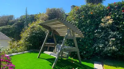 a wooden chair in the grass in a garden at Portmellon Cove Guest House in Mevagissey