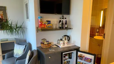 a room with a small refrigerator and a chair at Portmellon Cove Guest House in Mevagissey