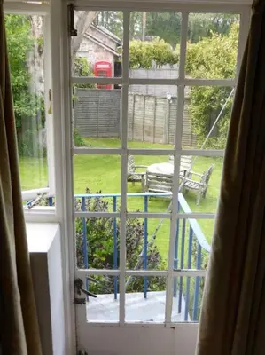 an open window with a view of a yard at Gamekeeper's Cottage within historic Tregrehan Garden in Par