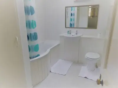 a white bathroom with a sink and a toilet at Gamekeeper's Cottage within historic Tregrehan Garden in Par