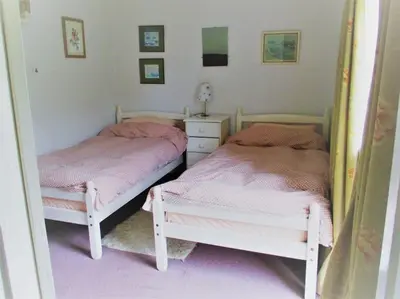 two beds sitting next to each other in a bedroom at Gamekeeper's Cottage within historic Tregrehan Garden in Par