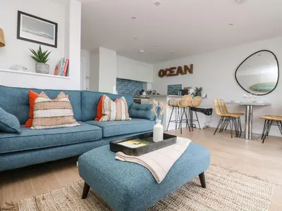 a living room with a blue couch and a table at Apartment 3 Fistral Beach in Newquay