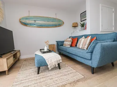 a living room with a blue couch and a tv at Apartment 3 Fistral Beach in Newquay