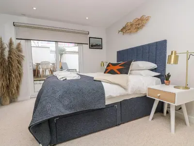 a bedroom with a large bed with a blue headboard at Apartment 3 Fistral Beach in Newquay