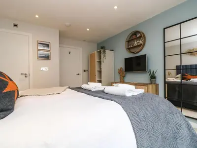 a bedroom with a large white bed and a tv at Apartment 3 Fistral Beach in Newquay