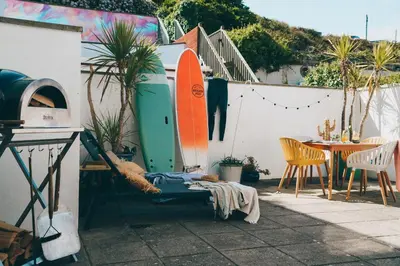 a patio with two surfboards and a table and chairs at Apartment 3 Fistral Beach in Newquay