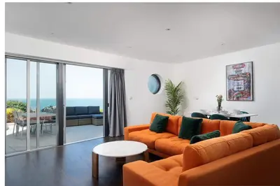 a living room with an orange couch and a table at Barepta Cove, Stunning Carbis bay apartment in Carbis Bay
