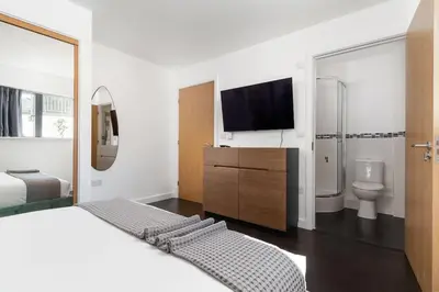 a bedroom with a bed and a tv and a bathroom at Barepta Cove, Stunning Carbis bay apartment in Carbis Bay